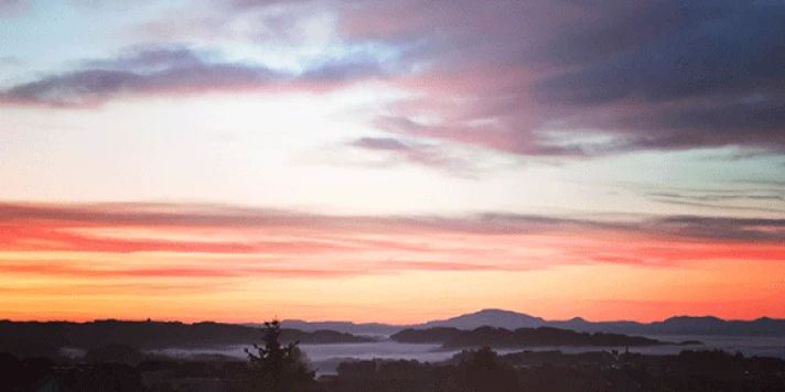 Aussicht auf Landschaft und rot gefärbten Himmel bei Sonnenuntergang.